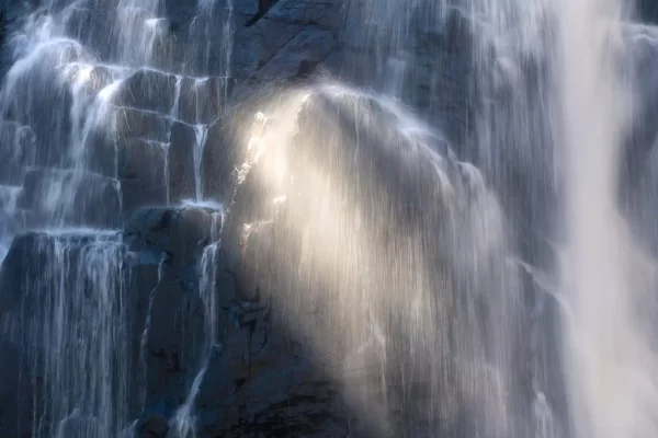 Long exposure photo of water falling at Mackenzie falls in the Grampians with light beams through it