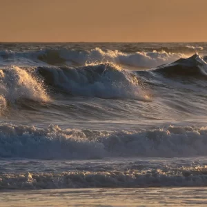 Waves breaking on the beach in golden light