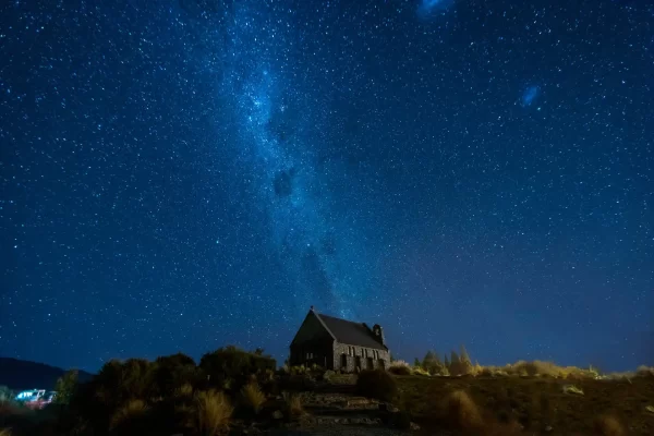 The stone church of the good shepherd at night with the Milky Way behind it