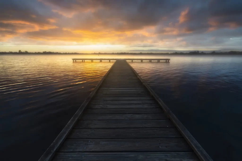 Fishing jetty at Lake Wendouree with a golden sunset and dark storm clouds