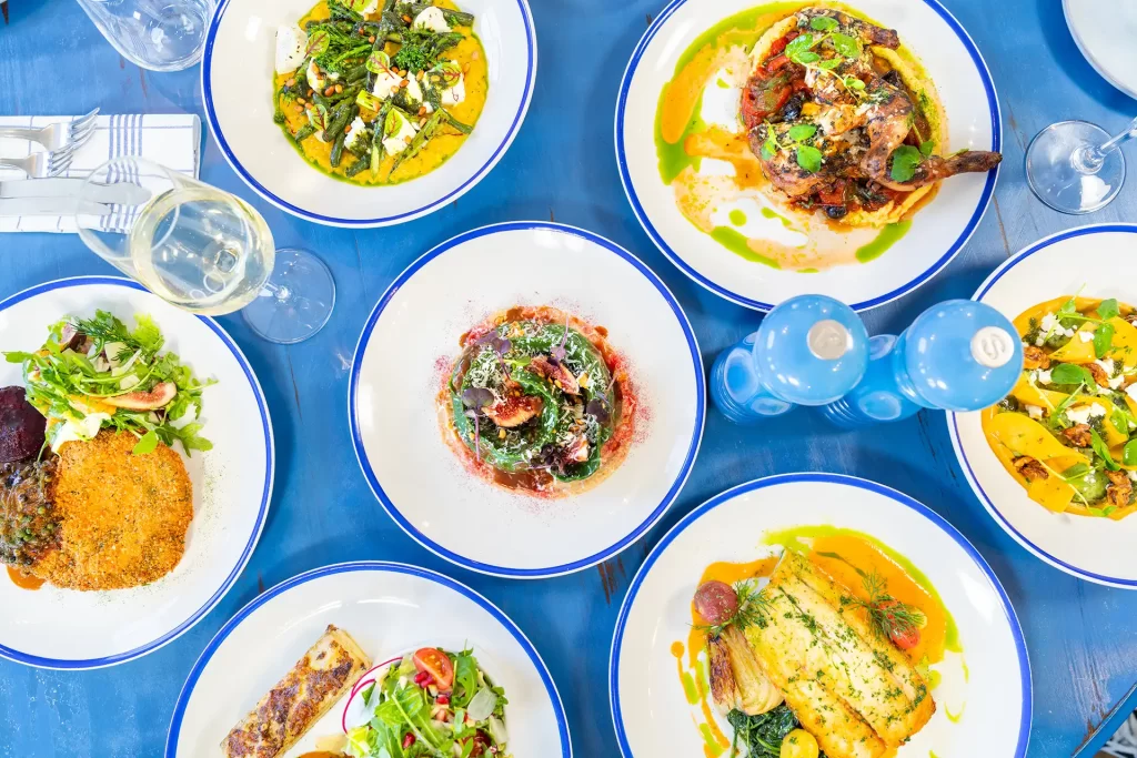 Flat lay product image of main courses on a blue table at a restaurant