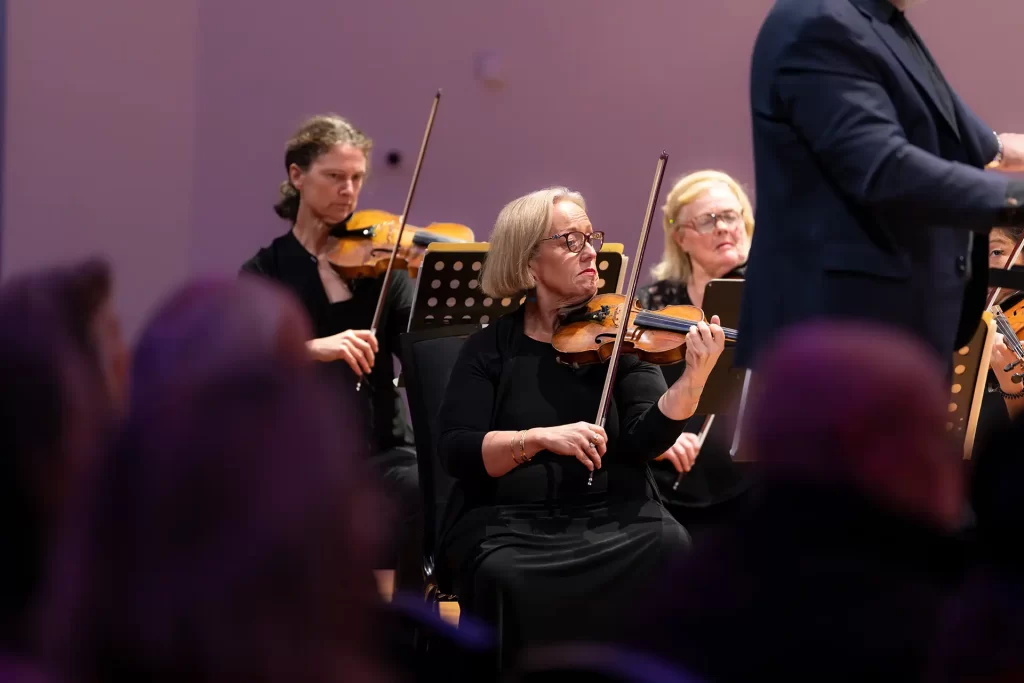 Commercial image of violinists performing with purple stage lights